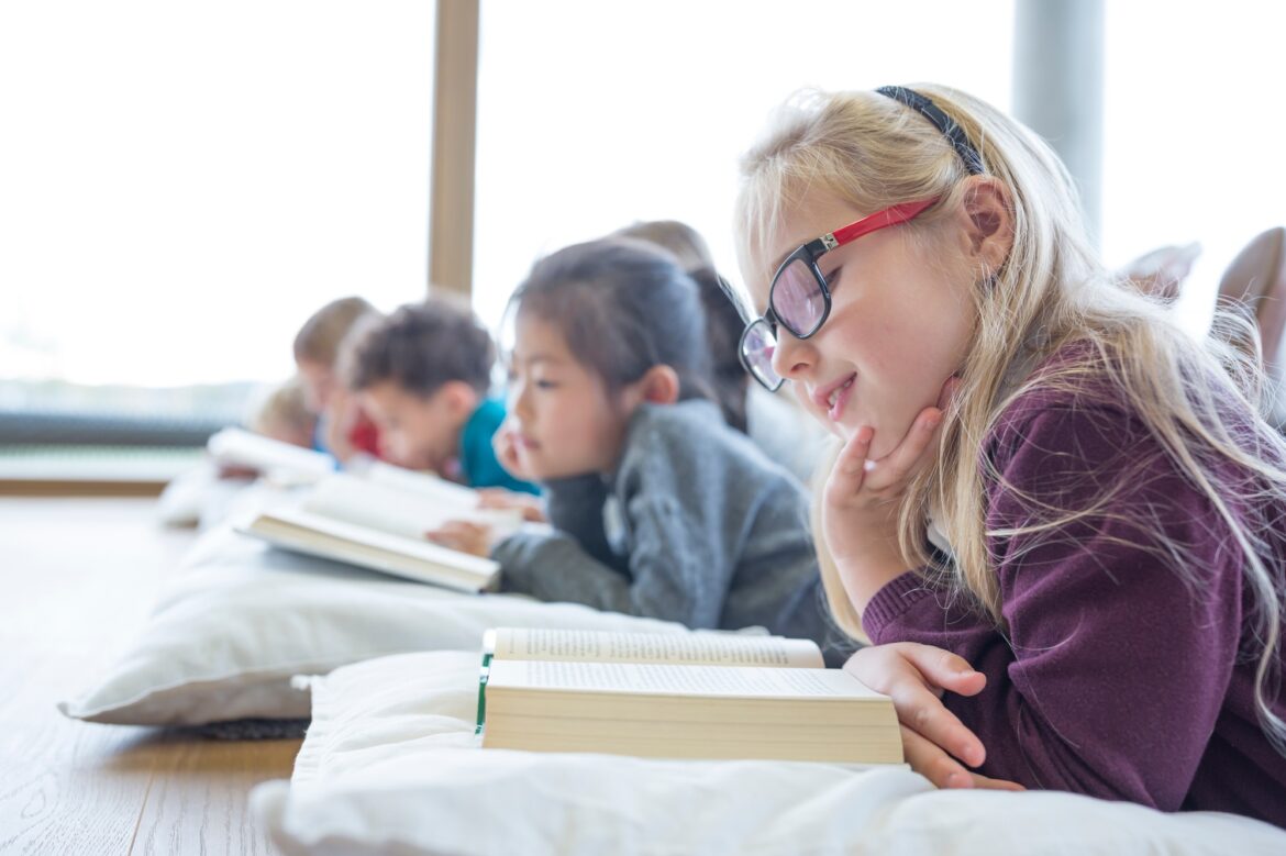 Pupils lying on the floor reading books in school break room